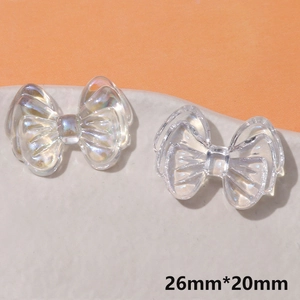 Vue macro de breloques nœuds en résine irisée et transparente, taille 26mm x 20mm