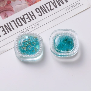 Detail of square resin charms with blue glitter, gold foil, and faux pearl edges
