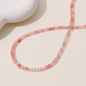 Close-up of heart-shaped pink beads for jewelry making on a minimalist white ceramic plate