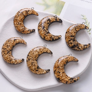 Close-up of crescent resin pendants with gold foil flakes and silver metal loops