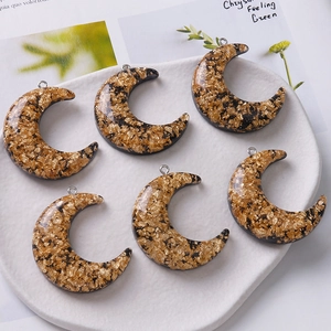 Macro shot of 6 crescent moon resin charms with gold foil in a ceramic dish