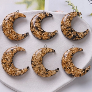 Macro detail of crescent moon pendants with gold leaf flakes and silver metal loops