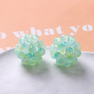 Macro view of handmade gradient light green and blue woven beaded spheres for accessories