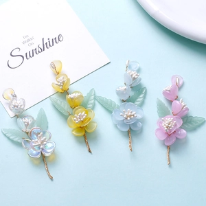 Detail of handmade resin flower charms with iridescent petals and green leaf accents