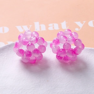 Handcrafted pink woven bead spheres for DIY jewelry on a white textured plate
