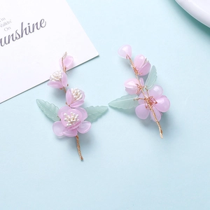 Macro detail of handmade floral hair pins with pink resin petals and green leaf accents
