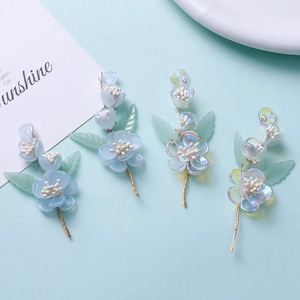 Detailed view of light blue resin flower hair clips with gold wire and green leaves