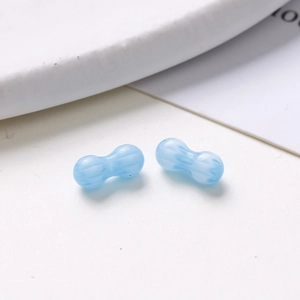 Macro shot of two light blue peanut-shaped glass beads with white swirl textures for DIY