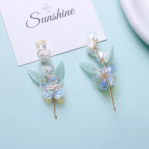 Detail of long floral drop earrings with iridescent petals and green frosted leaf accents
