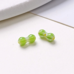 Macro view of peanut-shaped green and white striped glass beads for DIY jewelry making