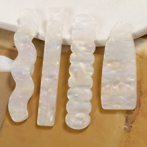 Schillernde Acryl-Wellenrechtecke für DIY-Haarspangen auf einer Marmoroberfläche