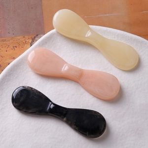 Outils de massage facial en résine crème, rose et marbre sur une assiette céramique