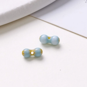 Macro shot of light blue dual-sphere glazed ceramic beads with yellow veins for DIY jewelry