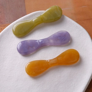 Trois barrettes nœuds en résine couleur olive, lilas et ambre avec texture marbrée sur plat blanc