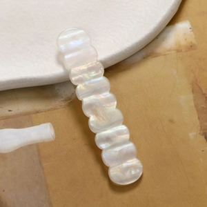 Nahaufnahme der perlweißen Acryl-Haarspange mit gewelltem Rand und Perlmutt-Glanz-Effekt