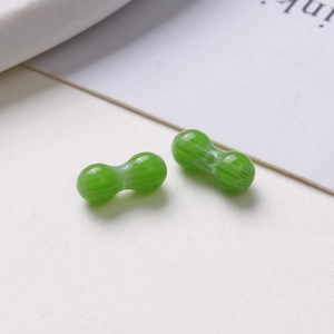 Detail view of two green peanut-shaped glass beads with textured surface for DIY jewelry