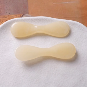 Gros plan de spatules de crème en résine beige avec texture pierre dans un plateau