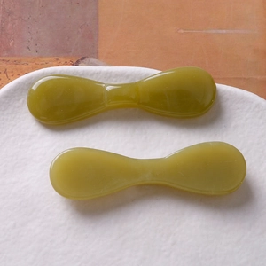 Vue détaillée de deux outils de massage en résine verte en forme de nœud sur une assiette