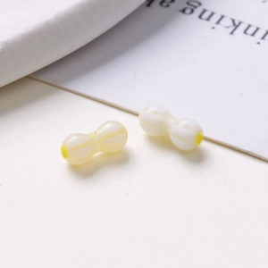 Detailed view of handmade peanut-shaped glass beads for DIY jewelry in white and yellow