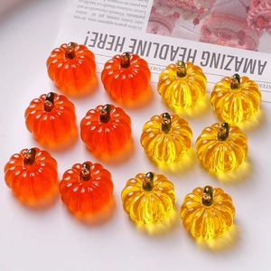 Macro detail of orange and yellow resin pumpkin charms with metal loops for DIY jewelry