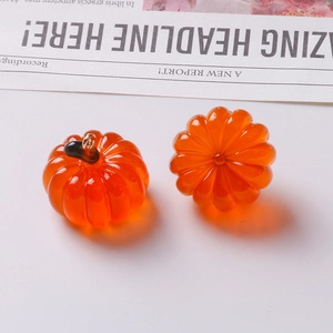 Detailed macro view of orange resin pumpkin pendants with gold loops for DIY jewelry making
