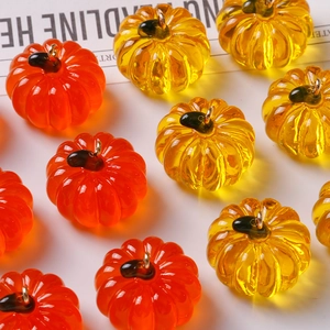 Macro shot of orange and yellow resin pumpkin charms with gold rings for DIY jewelry