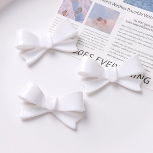 Three minimalist white acrylic bow hair clips displayed on a clean aesthetic background