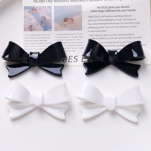 Detail of high-gloss black and white acrylic bow hair accessories on vintage background