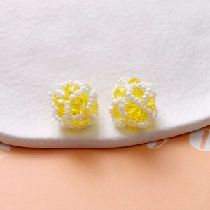 Detail of yellow faceted crystal and green seed beads in a handwoven spherical charm