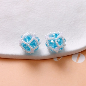 Detail of handmade beaded earrings featuring sky blue crystal balls and white seed beads