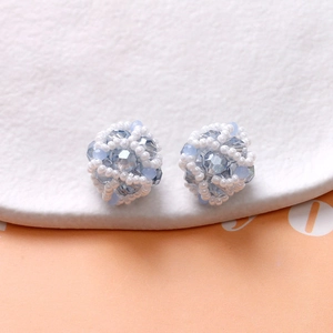 Macro shot of light blue faceted beads and white pearls hand-woven into a spherical earring
