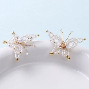 Detailed macro view of handmade bead butterfly charms with pearls and gold wire craft