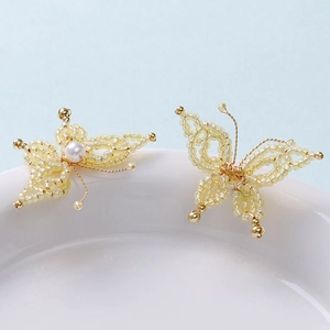 Detailed macro view of handmade yellow beaded butterfly pendant with small pearl accent