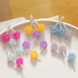 Handmade colorful seed bead cluster charms for jewelry making on a ceramic plate