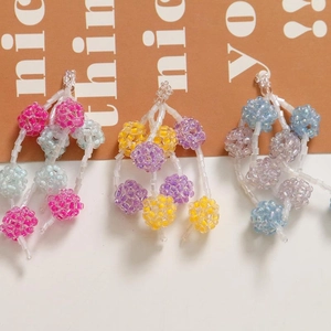 Detail of colorful beaded tassel earrings featuring handmade fruit-shaped ball charms
