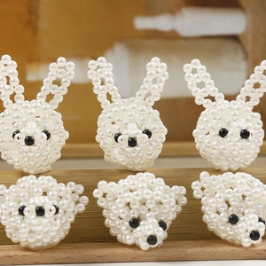Detalle macro de colgantes de perlas blancas hechos a mano con formas de conejo y oso
