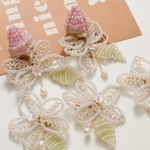 Detail of handmade beaded flower with pink core, white petals, and pearl droplet