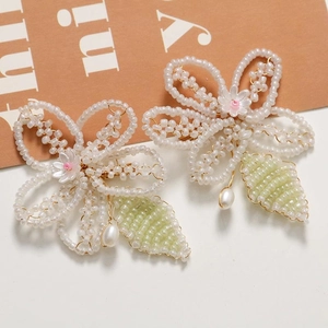 Close-up of handmade beaded flower with white and green petals and pink floral center