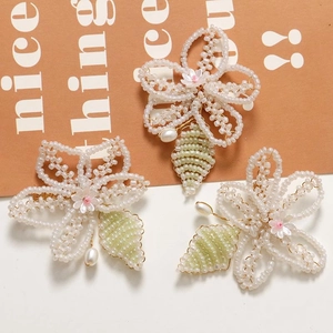 Handmade beaded flower hair clips with green leaves and pink floral accents on a card
