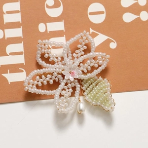 Detail of handmade woven pearl flower hairclip with green leaf and teardrop bead