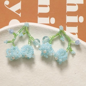 Detailed close-up of handmade lily of the valley beaded earrings in light blue and green