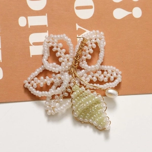Detailed close-up of handmade beaded flower craft with white pearls and gold wire