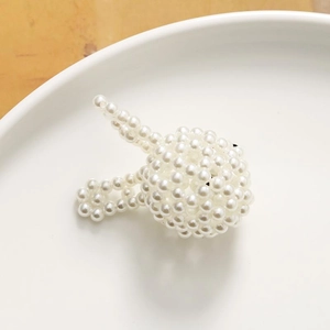 Detalle de una pinza para el pelo hecha a mano con perlas blancas de conejo