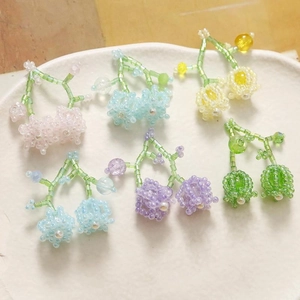 Handmade beaded lily of the valley earrings in various pastel colors on a ceramic tray