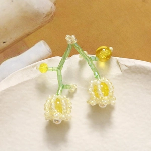 Macro shot of handmade lily of the valley beaded earrings with green and white glass beads