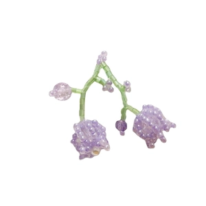 Handmade purple lily of the valley beaded earrings with green leaf accents on white background