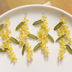 Detailed set of four handmade flower charms with yellow petals and green leaves