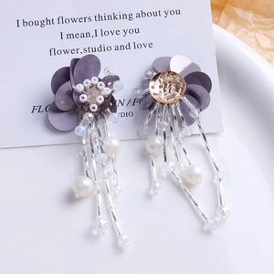 Détail d'une boucle d'oreille fleurie faite main avec pétales violets et longs pompons