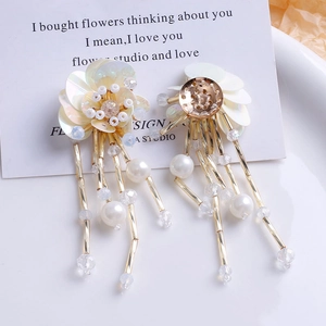 Détail de boucles d'oreilles bohèmes faites main avec franges, perles et paillettes dorées