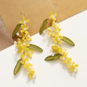 Detailed macro shot of handmade floral long earrings with yellow petals and green leaves